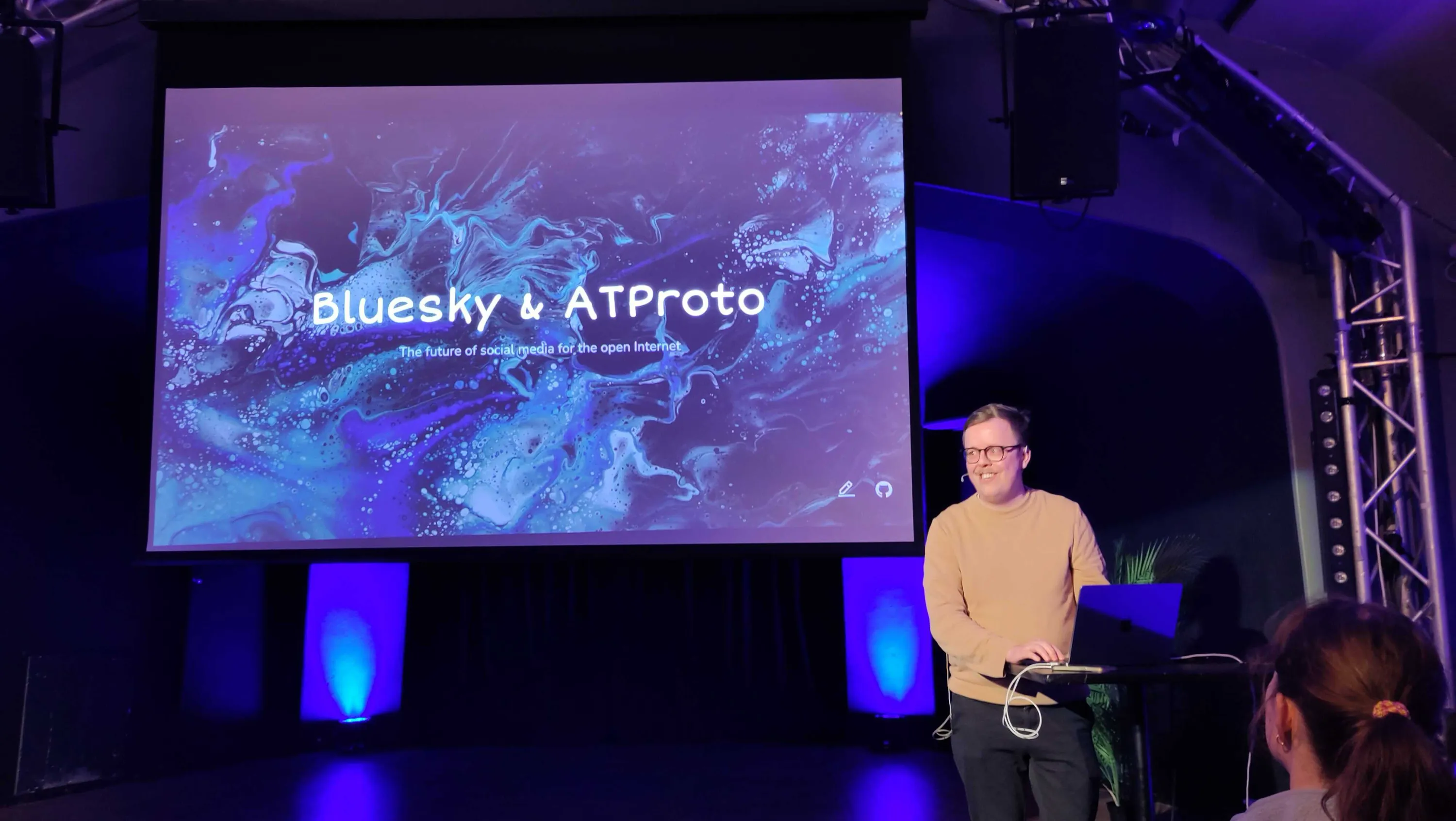 Snorre presenting at the Bergen Open Source Conference in front of a blue background with the Bluesky logo